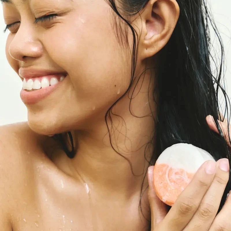 Woman laughing in the shower with a peach shampoo bar