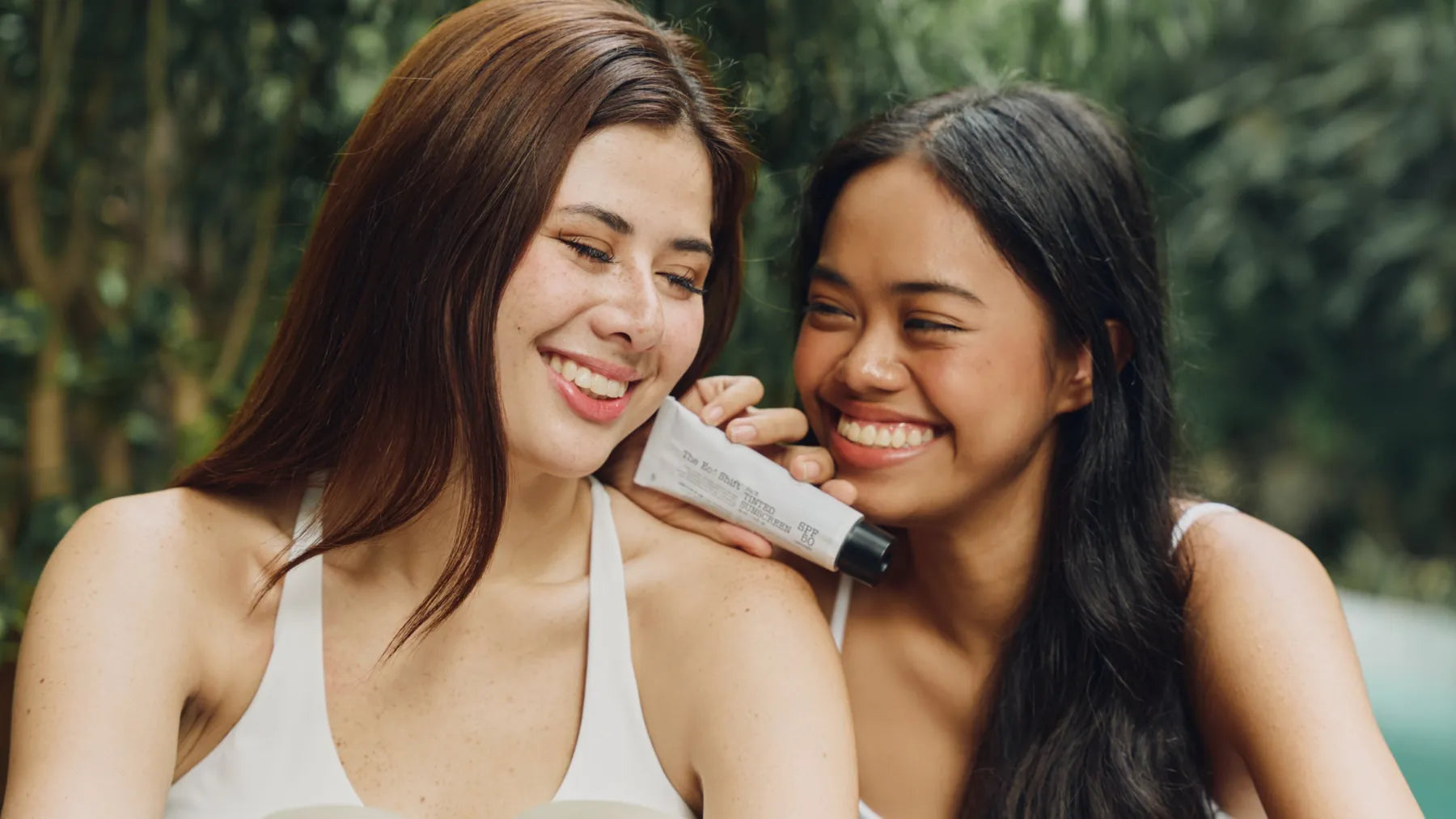 Two smiling women holding The Eco Shift Tinted Sunscreen SPF50